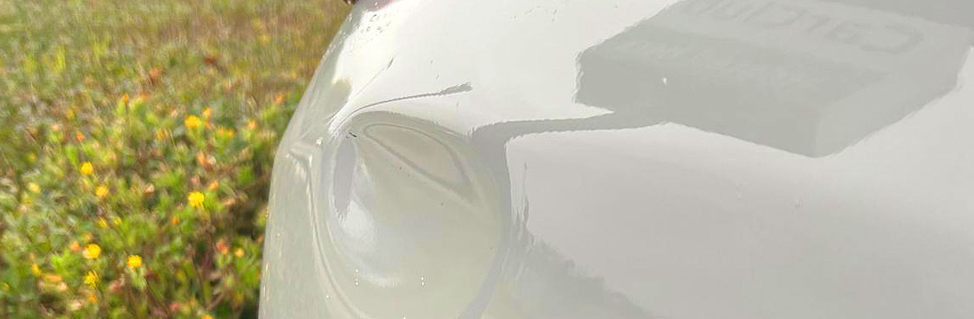 An image of a large dent on the side of a white car.