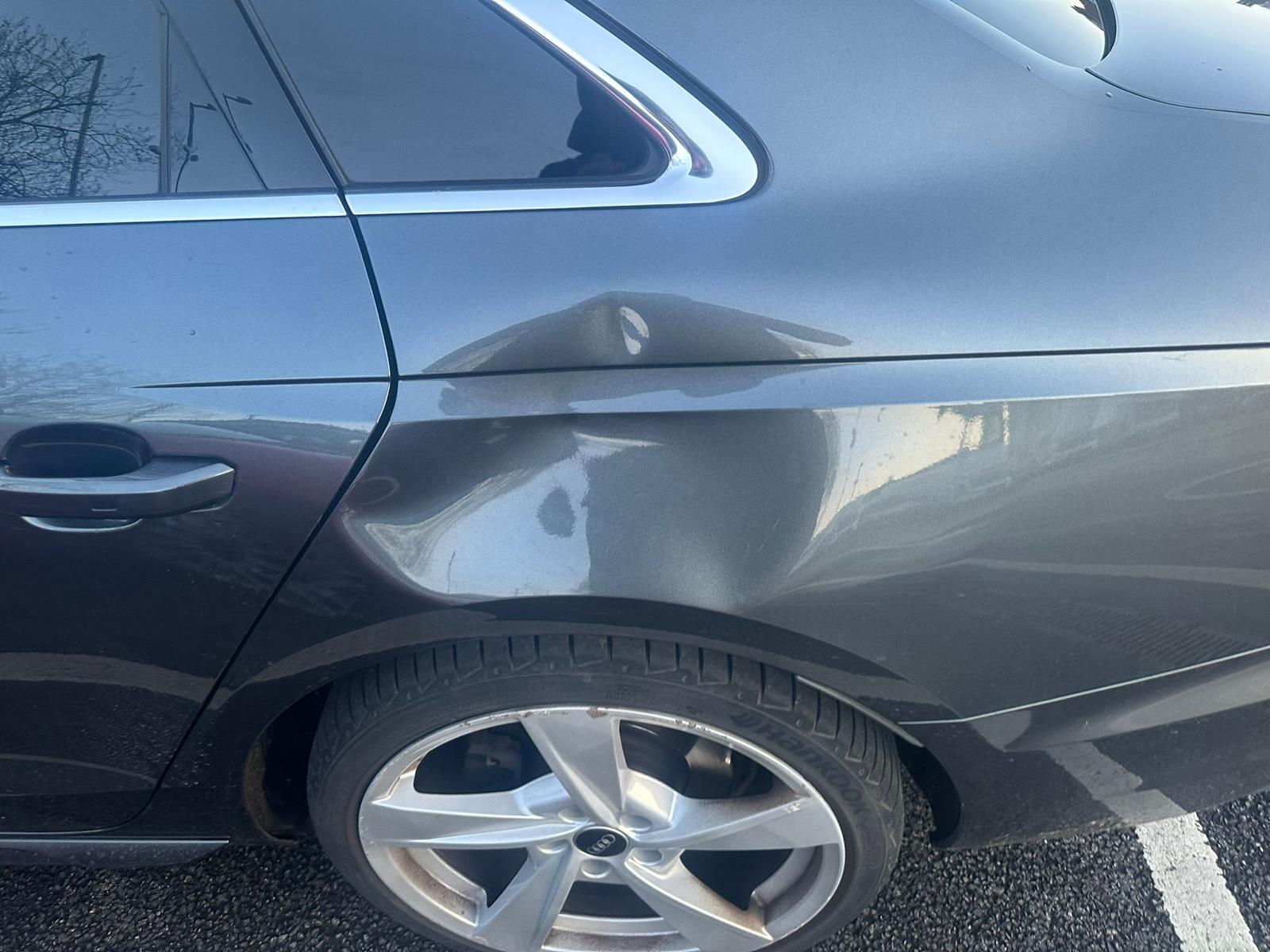 A dent on a dark grey car.