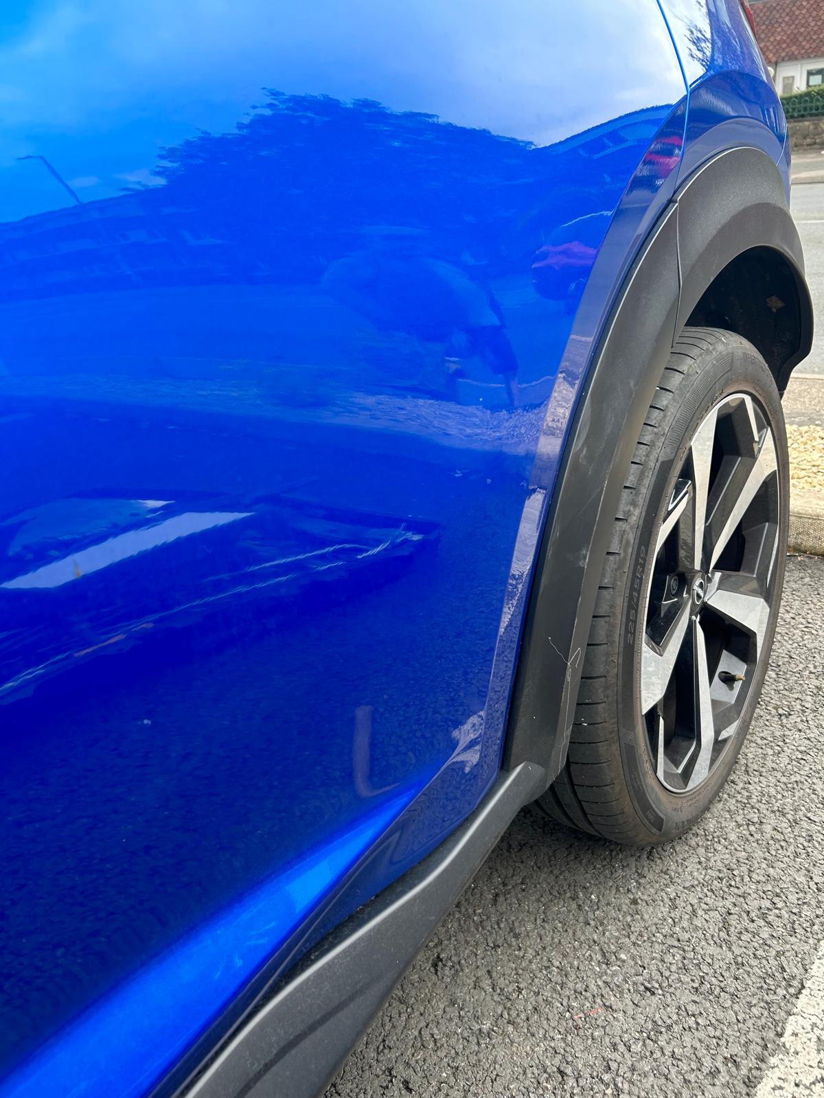 The dent on the royal blue Nissan is fixed.