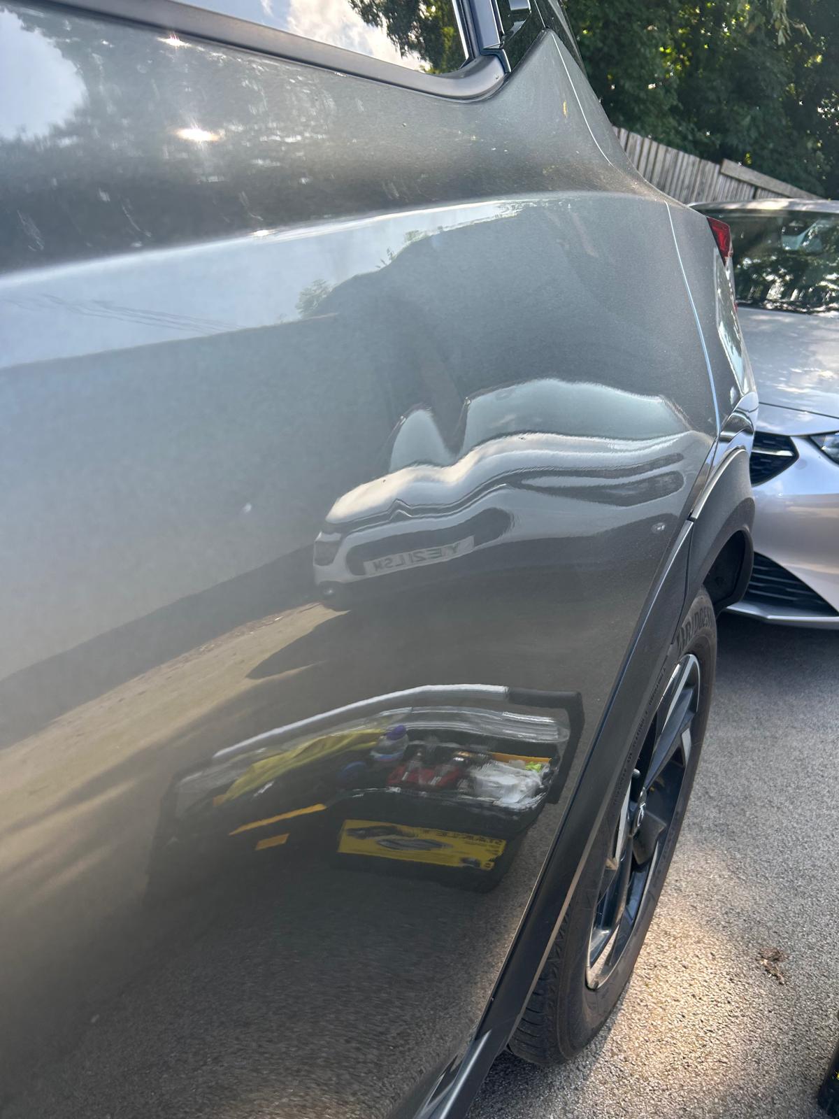 An image of a dent on a silver car.